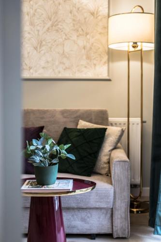 a living room with a couch and a table with a potted plant at Polpo Apartments B&B in Łódź