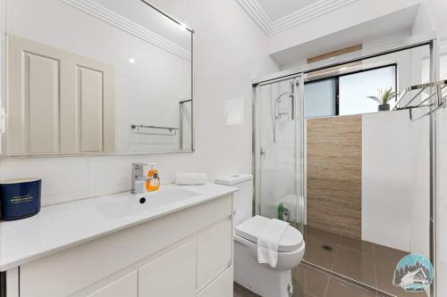 a white bathroom with a toilet and a shower at Aircabin - Carlingford - Sydney - 4 Beds House in Sydney