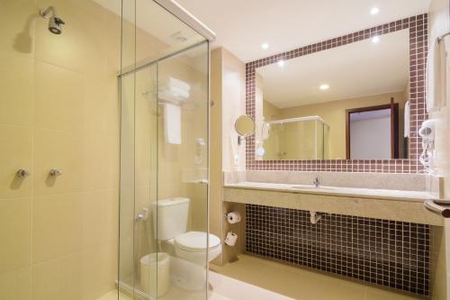 La salle de bains est pourvue de toilettes et d'une douche en verre. dans l'établissement Intercity Salvador Aeroporto, à Lauro de Freitas