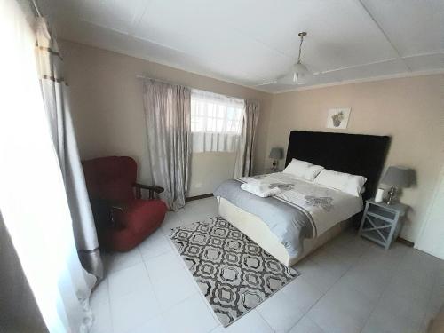 a bedroom with a bed and a red chair at The Villa in Bulawayo