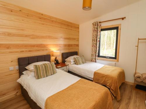 two beds in a room with wooden walls at Ash Lodge in Morpeth