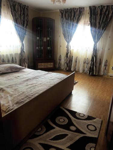 a bedroom with a large bed and two windows at Casa Ghețari in Gheţari