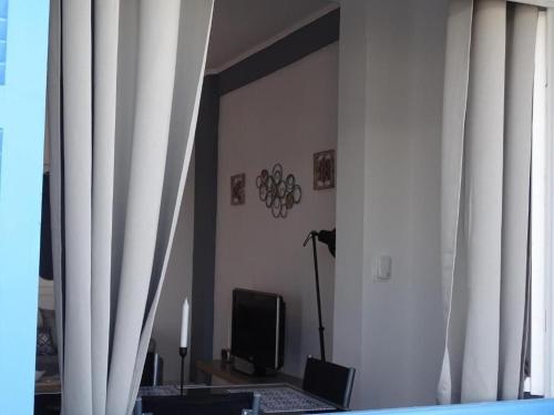 Cette chambre dispose d'une porte avec des rideaux et d'une télévision. dans l'établissement Splendid Santorini Villa | Bella Beach House | 3 Bedrooms | Private Terrace and Beautiful Sea Views | Monolithos, à Monolithos