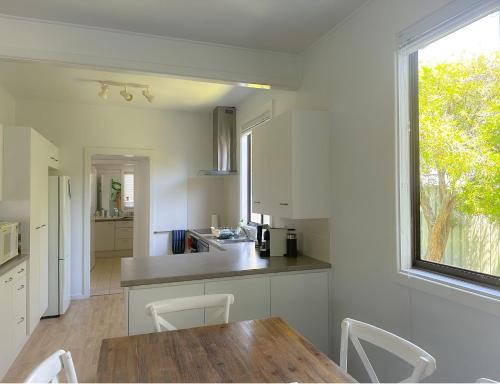 uma cozinha com armários brancos, uma mesa e uma janela em Yonder Cottage em Manyana