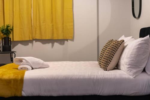 TQ luxurious 2 bed flat في برمنغهام: سرير مع كومة من الوسائد ومنشفة