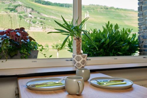a table with two plates and a vase and a window at Sonnenuhr in Bernkastel-Kues