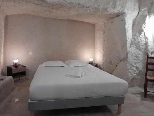 a bedroom with a large white bed in a stone wall at La troglodyte fantastique Lochoise in Loches