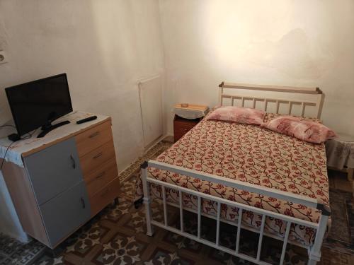 1 dormitorio con cama y vestidor con TV en ΜΟΝΟΚΑΤΟΙΚΙΑ ΣΑΛΑΜΙΝΑ, en Áyios Yeóryios