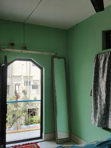 Habitación verde con espejo y ventana en Basama Complex, main road puttaparthi, en Puttaparti