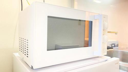 un forno a microonde bianco seduto sopra un lavandino di CON-TWO 201 a Tokyo