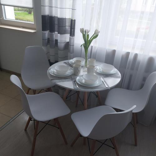 a white table with white chairs and a vase with flowers at Apartament Mazurska in Kętrzyn