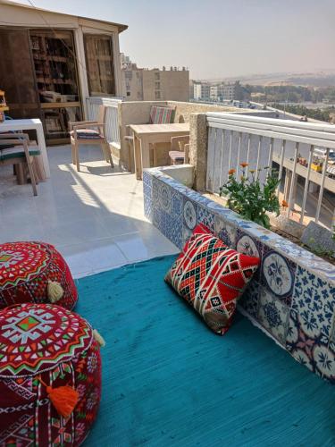 un balcón con almohadas en una alfombra azul en GEM VIEW ROOMS en Qaryat ash Shamālī