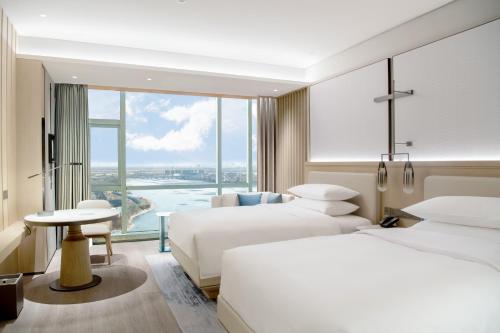 a hotel room with two beds and a large window at Qingdao Marriott Hotel Jiaozhou in Qingdao