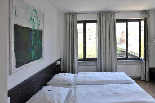 a bedroom with two beds and two windows at Tandem Hotel in Bamberg