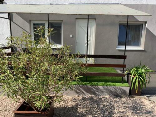 une maison avec un banc et des plantes devant elle dans l'établissement Mineral Rubin apartman, à Sóstófürdő