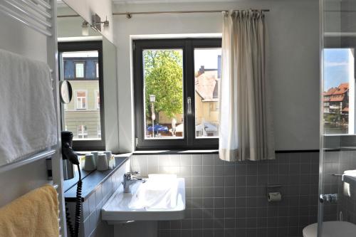 ein Bad mit einem Waschbecken und einem Fenster in der Unterkunft Tandem Hotel in Bamberg