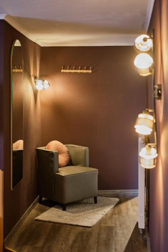 a living room with a chair and a mirror at Hotel Roter Hahn in Regensburg