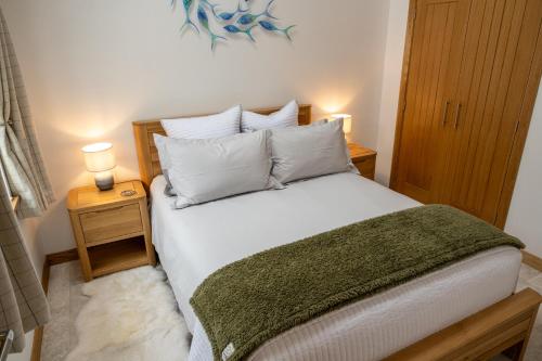 a bedroom with a bed with white sheets and pillows at Nana Cottage , Findhorn Village in Findhorn