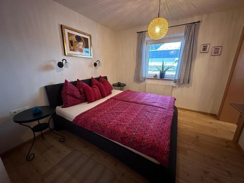 Schlafzimmer mit einem Bett mit roten Kissen und einem Fenster in der Unterkunft Kallis Appartement in Mayrhofen