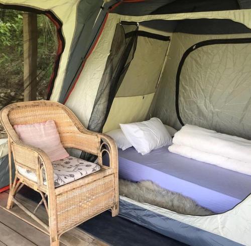 uma cadeira de vime e uma cama numa tenda em Back To Nature em Pokhara