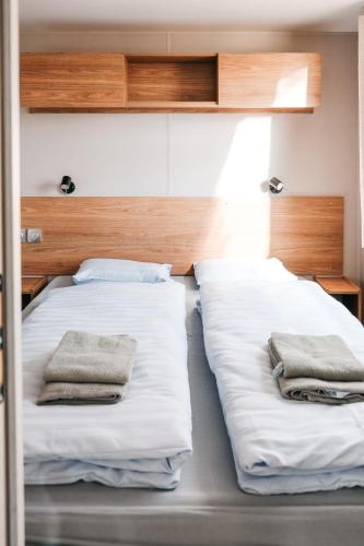 Dos camas en una habitación con toallas. en Pivoine Camping Belle-Vue 2000, en Berdorf