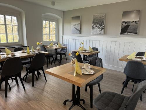 a dining room with tables and chairs and windows at Pension Nordwind in Hedwigenkoog