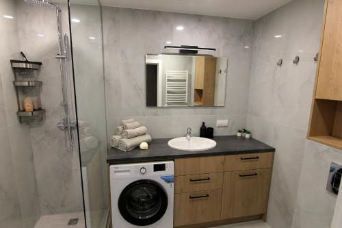 een badkamer met een wasmachine en een wastafel bij Warmzy Home - Modern 2 Rooms Apartment With Free Parking in Vilnius