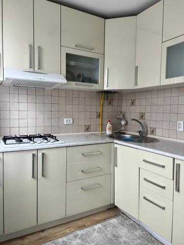 eine weiße Küche mit weißen Schränken und einem Waschbecken in der Unterkunft ИП.МЕДИНА in Taras