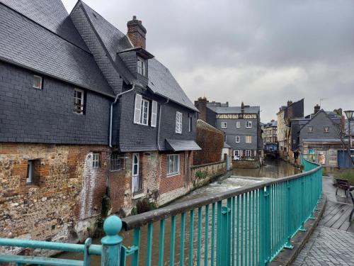 un groupe de bâtiments avec une clôture verte dans l'établissement Studio bucolique, à Pont-Audemer