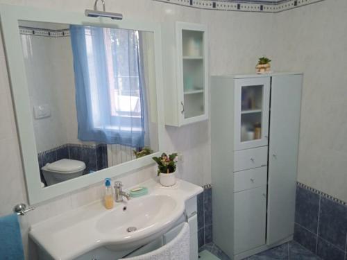 a bathroom with a sink and a mirror and a toilet at Villetta con parco vicino San Gimignano in Le Grazie