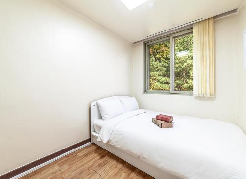 a white bedroom with a bed and a window at HK Resort in Sokcho
