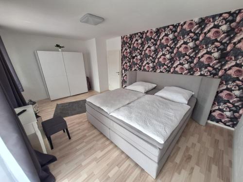 1 dormitorio con 1 cama y una pared con flores en Zur alten Scheune, en Ochtendung