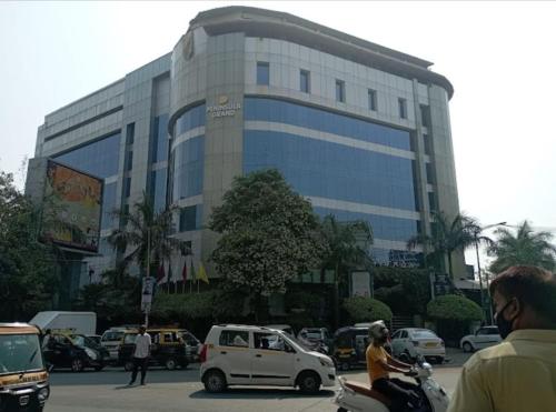 a large building with cars and people riding motorcycles in front of it at Hotel Adams Inn Near Mumbai Airport in Mumbai