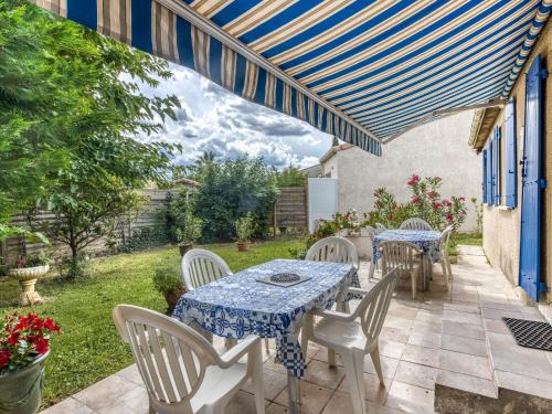 eine Terrasse mit Tischen und Stühlen und einem blauen und weißen Baldachin in der Unterkunft Pretty house with private fenced pool in Clarensac