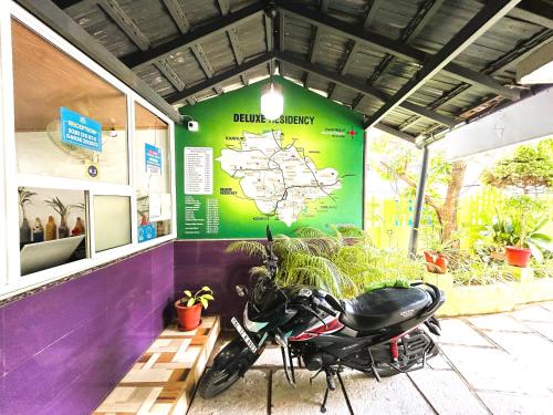 a motorcycle parked in front of a building with a map at Deluxe Residency in Kalpetta