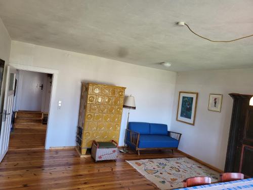 a living room with a blue chair and a door at Alte Schule Brodowin in Chorin