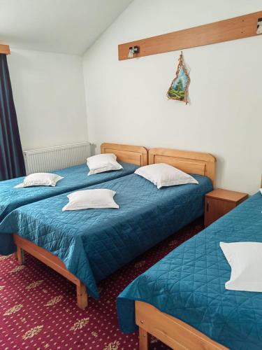 two beds in a room with blue sheets and white pillows at Pensiunea Cabana Veverita Valea Doftanei in Trăisteni