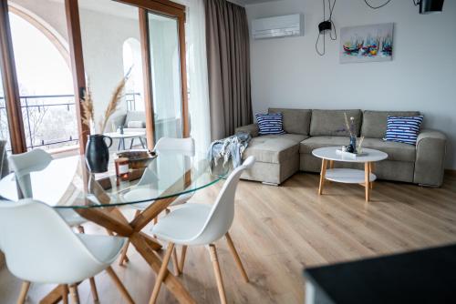 a living room with a glass table and white chairs at Queen's Palace Balchik apartment in Balchik