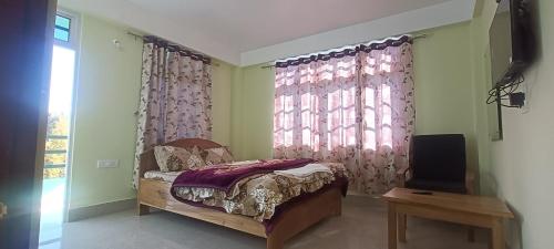 a bedroom with a bed and a tv and a window at ND HOMESTAY in Tawang