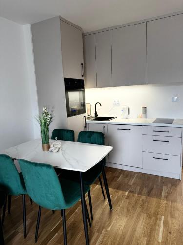 uma cozinha com uma mesa branca e cadeiras verdes em Apartament na Orkana em Rabka-Zdroj