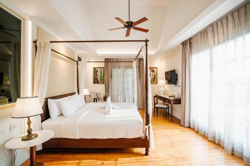 a bedroom with a canopy bed and a desk at Buri Sriping Riverside Resort & Spa in Chiang Mai