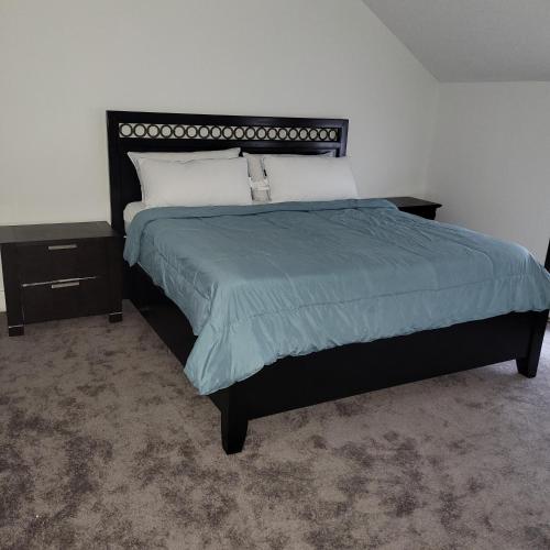 Schlafzimmer mit einem großen Bett mit blauer Decke in der Unterkunft Entire house - 4 Bedroom-Enfield in Enfield