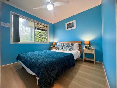 a blue bedroom with a bed and a window at Folk-style Waterford 3 bdr-house in Kingston