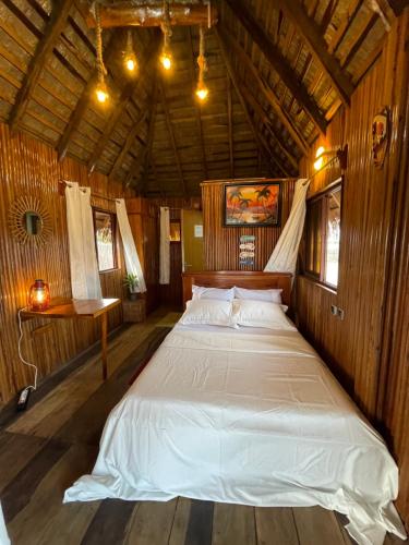 una camera da letto con un grande letto in una camera in legno di TATA BEACH a Cadjèhoun
