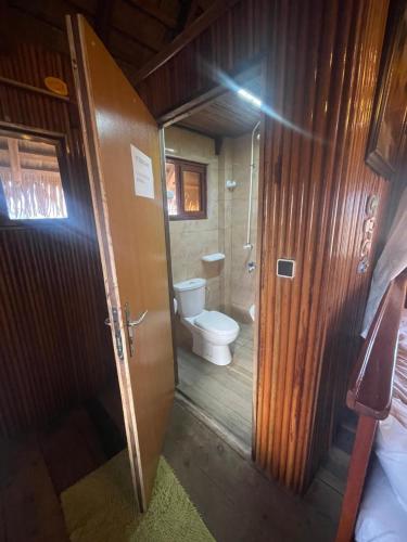 La salle de bains est pourvue de toilettes et d'une porte en bois. dans l'établissement TATA BEACH, à Cadjèhoun