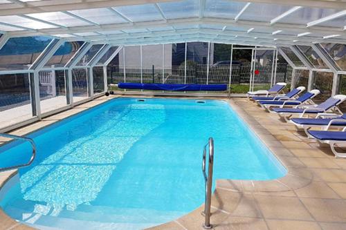 een groot zwembad met blauwe stoelen in een gebouw bij Studios - Location de vacances Le Trécelin in Plévenon