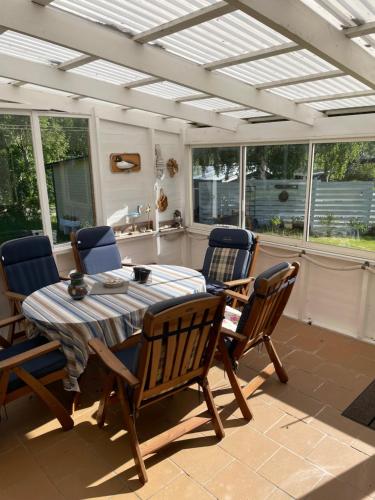 a table and chairs on a patio with a ceiling at Nice child-friendly house 200m from beautiful beach,near Kullaberg in Farhult