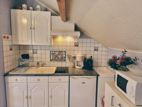 a small kitchen with white cabinets and a sink at LE CROSERY Clim Rando Ski Gorges Voie Verte in Thiéfosse