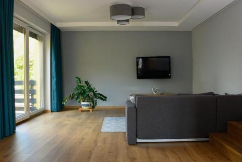 sala de estar con sofá y TV de pantalla plana en Hotelik u Sąsiada, en Olsztyn