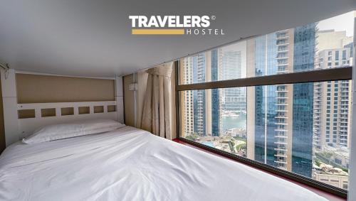 a bedroom with a bed and a large window at Travelers - Dubai Marina Hostel in Dubai